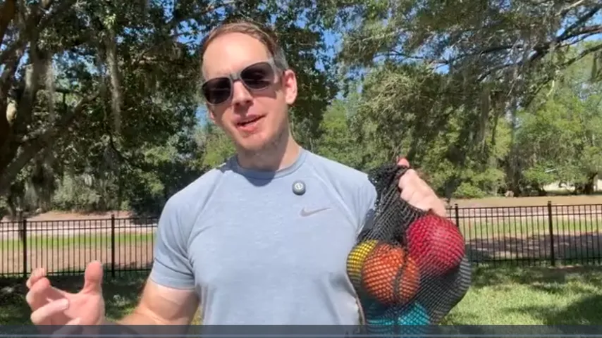 Coach presenting the weighted-ball set in its mesh carry bag
